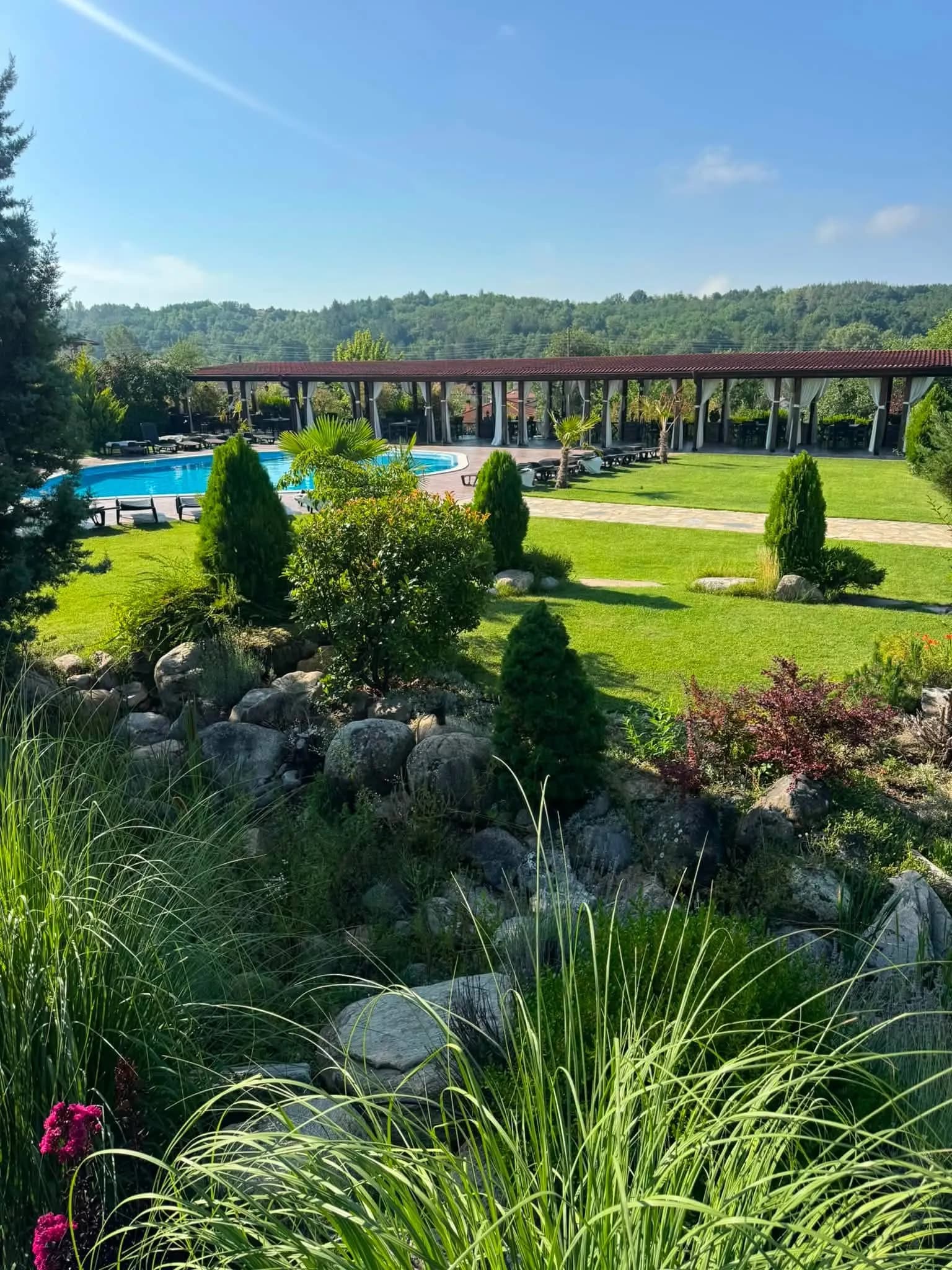 The outdoor pool and the lawn in the gardens of Bozhe Ime Spa & Park