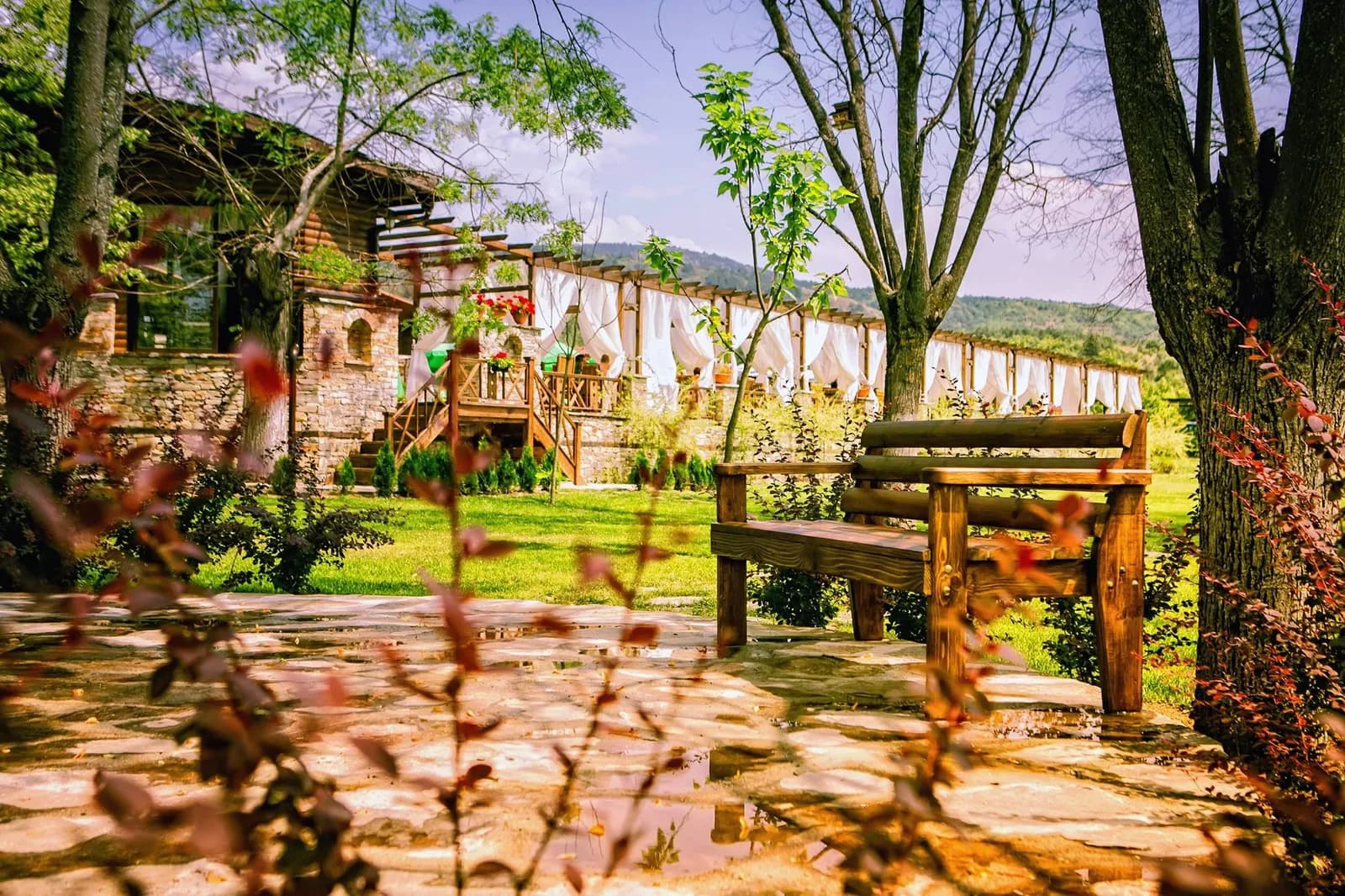 Градинската тераса на ресторанта в Боже Име Spa & Park, с перголата и дървения мост